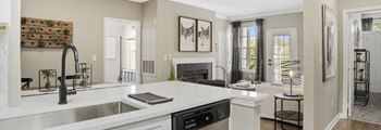 Double Sink With Integrated Sprayer a kitchen with a sink and a dishwasher in front of a living room with a fireplace